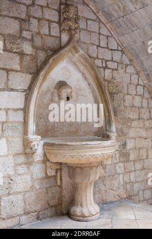 Dubrovnik, Dubrovnik-Neretva, Croatia. Ancient stone fountain in atrium of the Rector's Palace. Stock Photo