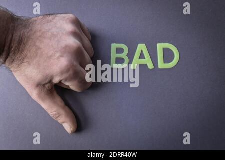 Thumb down beside the word Bad written with plastic letters on gray paper background, concept Stock Photo