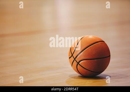 Orange basketball ball on wooden parquet. Close-up image of basketball ball over floor in the gym Stock Photo