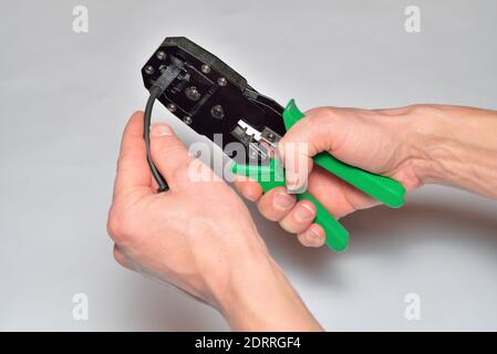 Hands of the installer of computer networks crimped connector on the cable Stock Photo