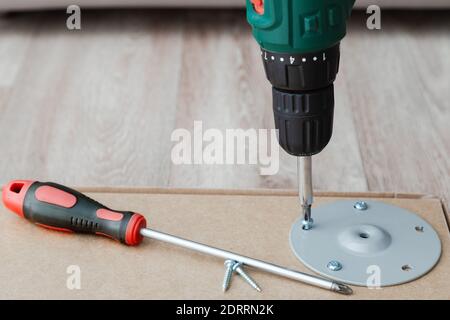 Drill screwdriver and screw. Furniture desk table assembling. Professional renovation home tools for carpentry and wood DIY Stock Photo