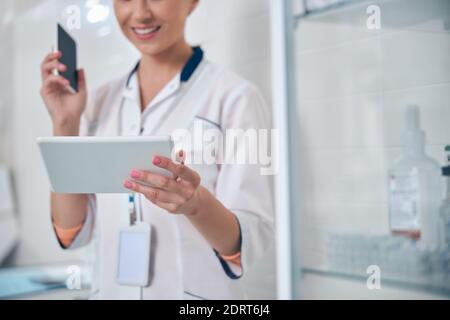 Smiling female dentist using gadgets in office Stock Photo