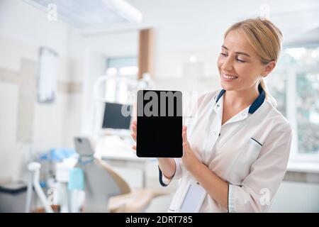 Happy female dentist using tablet at work Stock Photo