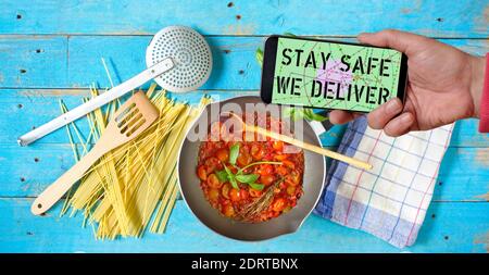 COVID-19 'STAY SAFE WE DELIVER' Coronavirus social distancing restaurant business smartohone with text offering online food delivery Stock Photo