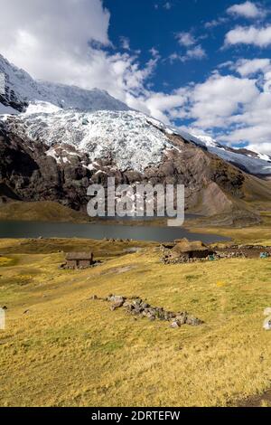 Huge glaciers on the eastern face of Ausangate mountain above permanent houses at 4900 m, Ausangate hike, Peru, South America. Stock Photo