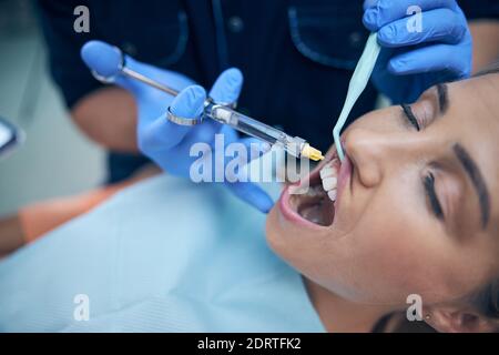 Dentist doing injection in woman gum in office Stock Photo