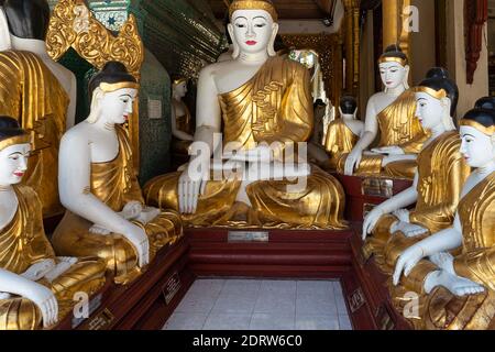 Lot of Sculptures of Seated Buddha in Golden Robe. Shwedagon Pagoda Temple. Yangon Myanmar 2019 Stock Photo
