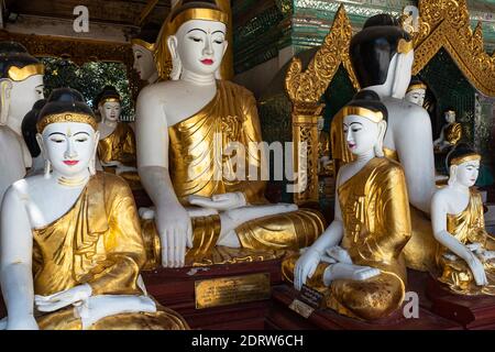 Numerous Sculptures of Seated Buddha in Golden Robe. Shwedagon Pagoda Temple. Yangon Myanmar 2019 Stock Photo