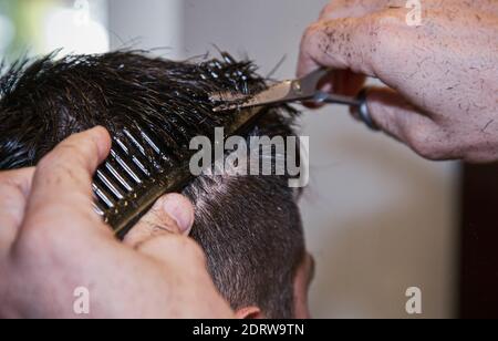 Cut and combine. Close-up photo of a man having his hair cut with a comb and scissors. Stock Photo
