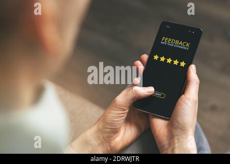 customer feedback - woman using phone to give 5 star rating for good service Stock Photo