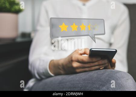 customer review - woman using phone to give feedback and rate her experience with stars about service or product quality Stock Photo