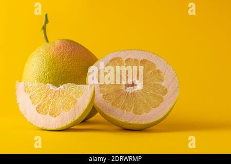 horizontal view in foreground of a half grapefruit grapefruit and grapefruit slice isolated on yellow background Stock Photo