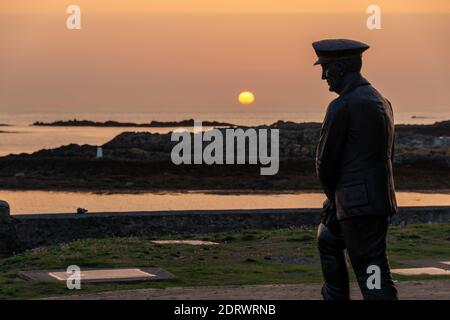 Bronze statue of Admiral Sir Max Horton looking out to sea as the sun goes down at Rhosneigr on Anglesey where he was born. Stock Photo