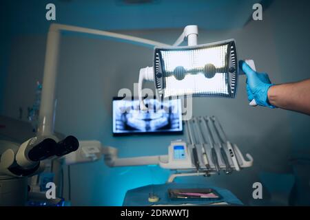 Modern dental surgery. Dentist adjusting lamp against x-ray of teeth in dental clinic. Stock Photo