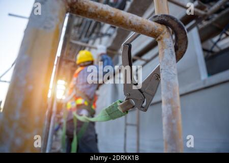 Construction worker wearing safety harness and safety line working at high place, Fall arrestor device for worker with hooks for safety body harness o Stock Photo