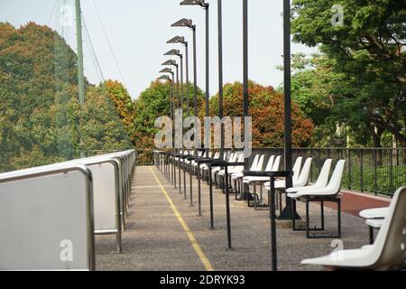 Empty Chairs On Footpath Against Trees