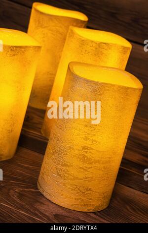 Four golden LED wax candles against wooden background Stock Photo