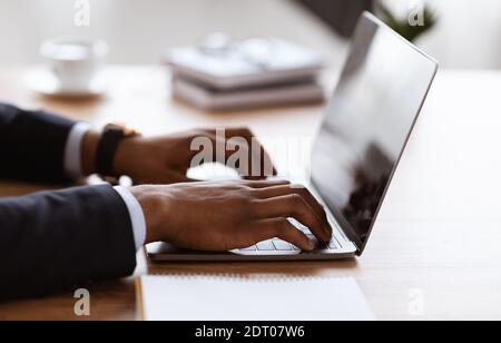 Side view of black manager typing on modern laptop Stock Photo