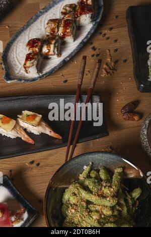 A vertical shot of a variety of sushi and nigiri and wakame salad on table served in ceramic plates. Stock Photo