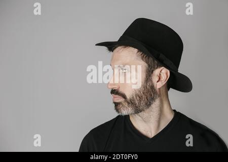 Profile portrait of a handsome bearded middle-aged man with hat against neutral background Stock Photo