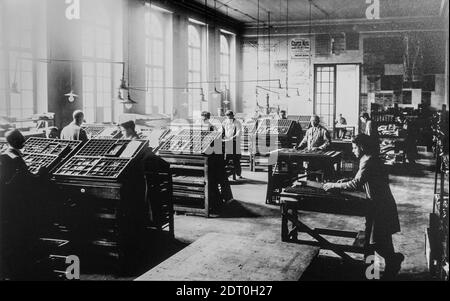 Early 20th century typesetters arranging types called typesetting for letterpress printing in print shop / printing office Stock Photo