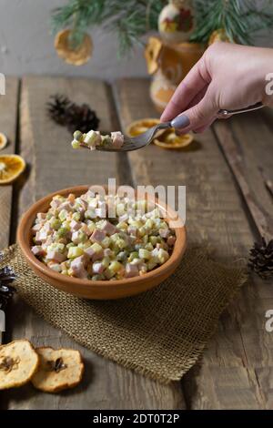 Traditional Olivier salad russian in a bowl on a wooden background. Festive Russian cuisine. Copy space. Rustic style. Vertical orientation. Stock Photo
