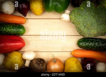 Fresh vegetables are laid out on the table as a background with space for text. Frame of vegetables, paprika, potatoes, onions, carrots, zucchini, mus Stock Photo