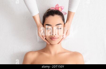 Young asian woman enjoying skin lifting face massage at wellness center Stock Photo
