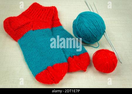Socks made of multi-colored woolen threads. DIY knitted socks. Woolen knitted socks and threads and knitting needles Stock Photo