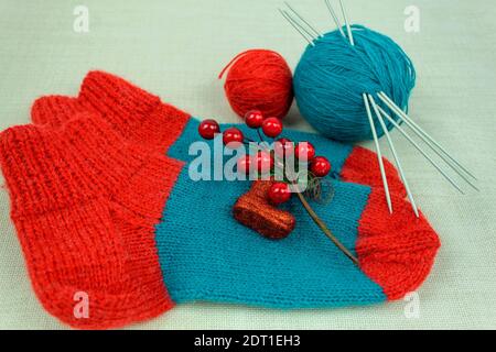 Socks made of multi-colored woolen threads. DIY knitted socks. Woolen knitted socks and threads and knitting needles Stock Photo