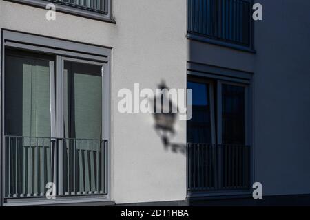 A shadow of a typical Maastricht street lamp on the facade of an appartment building making it looks like to lamp is attached to the balcony as the li Stock Photo