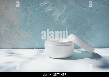 Opened white jar with moisture face cream on concrete background with shadows Stock Photo