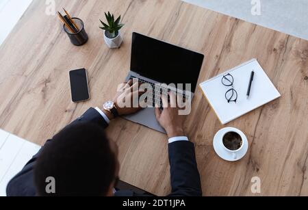 African businessman typing on laptop with blank screen, top view Stock Photo