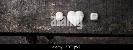 I love you sign spelled on wooden dicer with marble made heart in the middle. Over rustic wooden background. Stock Photo