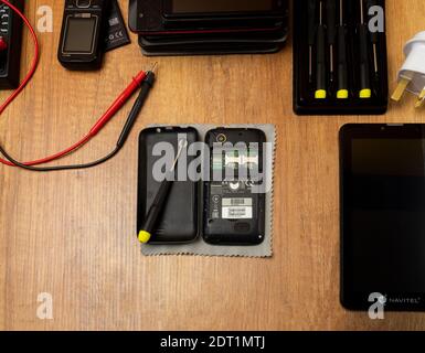 Disassembled mobile phone and tools on a wooden table Stock Photo