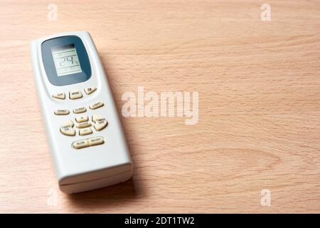 Air conditioner remote set at 24 degrees celsius on wooden desk. Concept of energy saving and environmental protection. Copy space. Stock Photo