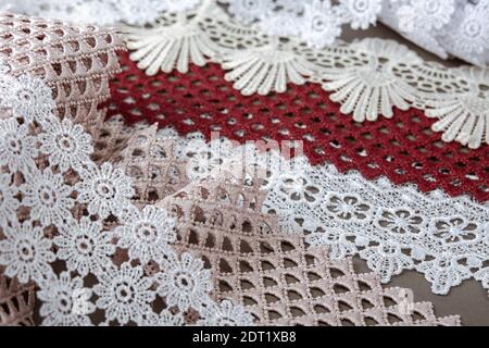 pile of red, white. beige set sail champagne gentle luxury quality guipure, lace fabric on gray background. use for sew clothes linen decoration. Stock Photo