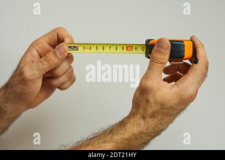 Hand of repairman holding a tape measure over white background Stock Photo