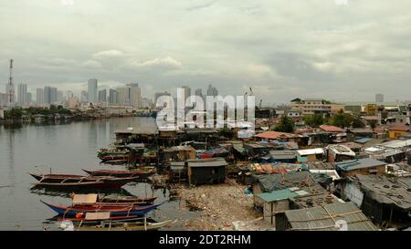 Shacks in the slums of Manila in a poor district and skyscrapers of a big city, aerial view. Stock Photo