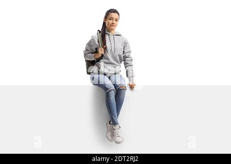 Mixed race female student sitting on a blank board and smiling at camera isolated on white background Stock Photo