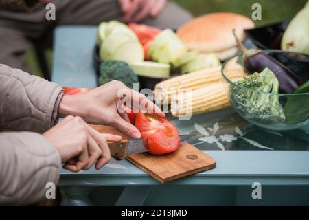 Joyful efforts to prepare for a family holiday in the yard. Hands of a man and a woman preparing vegetables for grilling for a picnic. Without a face Stock Photo