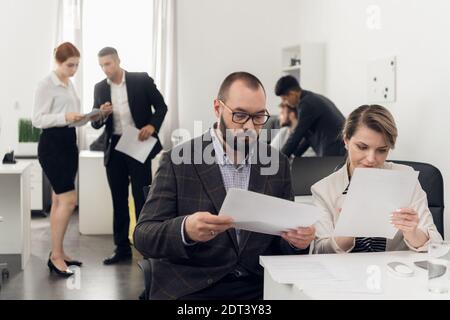 young self-made businessmen in the office discuss a new startup, share business ideas and directions of the company's development. Stock Photo