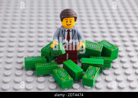 Tambov, Russian Federation - December 19, 2020 Lego businessman minifigure standing in a pile of cash. Stock Photo