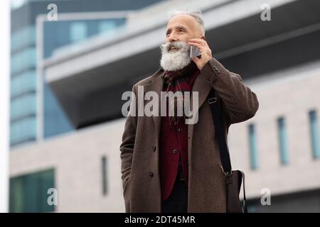 Wealthy senior man having conversation on phone outdoors Stock Photo