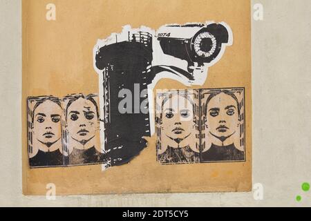 Graffiti cut outs pasted on a wall depicting a surveillance camera and female Stock Photo