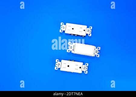 Switch and two sockets without covers, photo against blue background Stock Photo