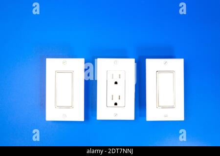 Two switches and a socket complete with covers, photo against a blue background Stock Photo