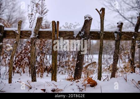 Close up of winter scenery fence made of wood stick branches lining up garden in snow Stock Photo