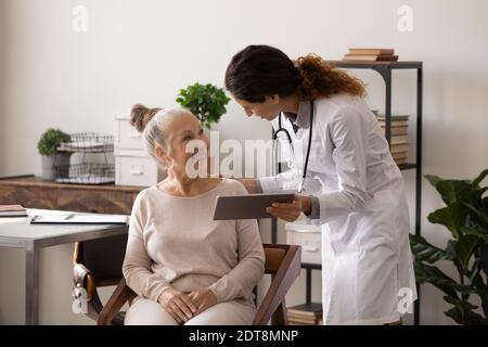 Female doctor consult senior patient using tablet Stock Photo