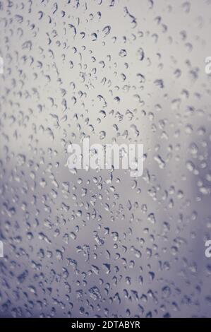Melting snow on the glass, drops of water condensation on the window, and transparent glass of the window in cold winter, winter landscape outside the Stock Photo